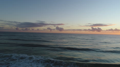 Luftaufnahme-Eines-Wunderschönen-Sonnenaufgangs-über-Einem-Ruhigen-Meer-Mit-Einem-Paddelnden-Surfer-Am-Miami-Beach,-Gold-Coast,-Australien