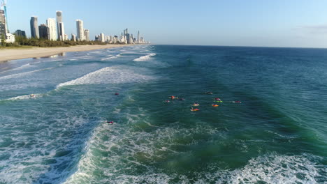 Aerial-view-of-a-group-of-Nippers-paddling-out-on-boards-during-a-morning-training-session-at-Mermaid-Beach-Gold-Coast-Australia