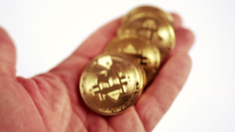 Bitcoin-Kryptowährung-–-Goldene-Bitcoin-Münzen-In-Der-Hand-Halten-Und-Umdrehen,-Dann-Auf-Den-Tisch-Legen