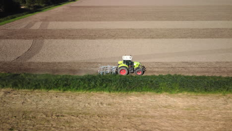 Luftaufnahme-Eines-Traktors,-Der-Ein-Landwirtschaftliches-Feld-Mit-Egge-Bearbeitet,-4k