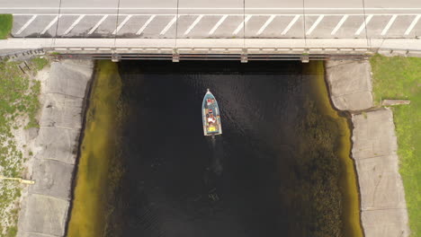 A-top-down-drone-shot-over-a-boat-in-a-canal-on-a-cloudy-day
