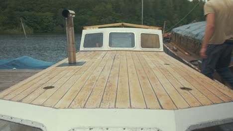 Carpenter-walking-along-deck-of-wooden-boat-repair-project