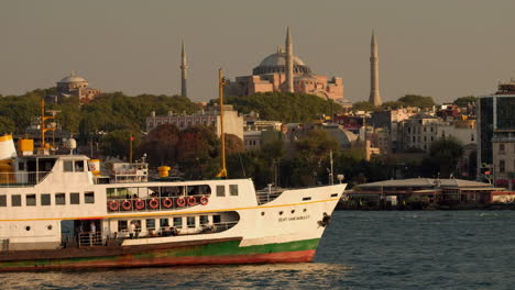 Telephoto,-static-clip-of-old-Istanbul-ferry-slowly-passing-the-Hagia-Sophia-at-sunset-in-Istanbul