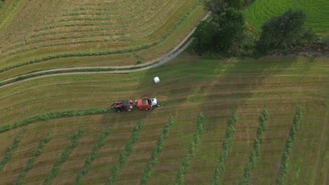 Silage-Bale-Wrapper-And-Grass-Turner-Farm-Machinery-At-Work-On-Farmland,-Norway