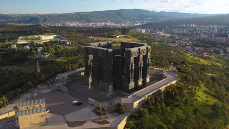 Aerial-arc-shot-of-Chronicle-of-Georgia-monument-overlooking-Tbilisi-sea