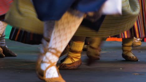 Adult-female-dancers-in-traditional-folk-costumes-perform-in-a-dance-performance-in-open-air,-happy,-Latvian-national-culture,-close-up-shot-of-feet-with-simple-footwear-made-of-one-piece-of-leather