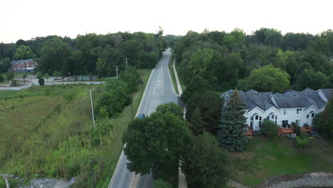 Elevated-aerial-footage-following-a-car-as-it-travels-down-a-suburban-neighborhood-of-America