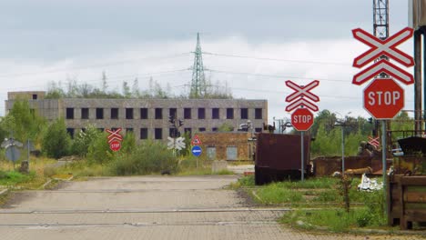 Exterior-view-of-abandoned-Soviet-heavy-metallurgy-melting-factory-Liepajas-Metalurgs-territory,-empty-street,-STOP-signs-at-railway,-overcast-day,-wide-shot