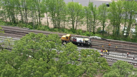 an-aerial-view-over-trees-looking-at-men-fixing-train-tracks-on-a-sunny-day