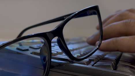 Eyeglasses-Resting-On-Keyboard-With-Hands-Typing