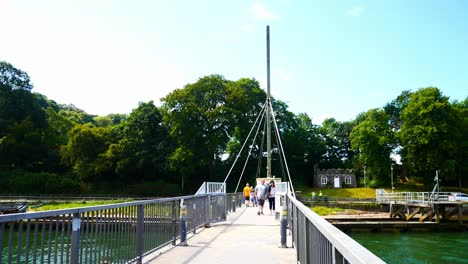 Visiting-tourists-walking-across-sunny-Caernarfon-cantilever-swing-bridge-crossing