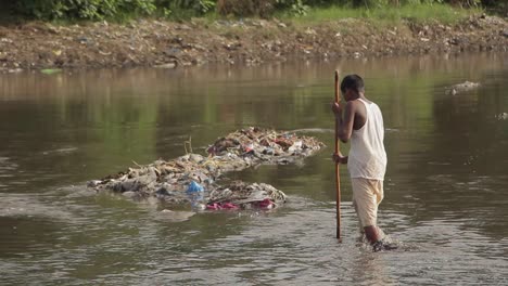 Niño-Paquistaní-Caminando-Por-Un-Sitio-De-Eliminación-De-Desechos-Tóxicos-En-El-Agua-Del-Río