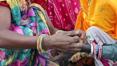 Indian-woman-from-rural-village-ties-pooja-or-puja-bracelet-on-friend-wrist-as-sisterhood-concept