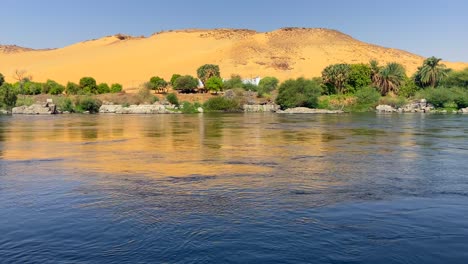 Little-oasis-landscape-on-the-banks-of-the-Nile-with-a-huge-dune-with-many-green-vegetation-at-its-base
