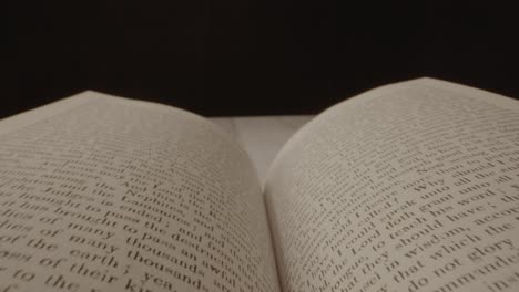 A-camera-shot-floating-across-an-open-book-with-a-black-background-and-the-book-is-later-closed