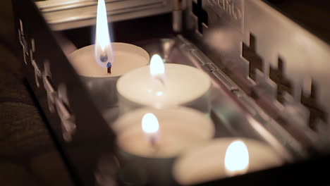 Close-up,-lighting-up-small-candles-in-metal-container-with-match-stick