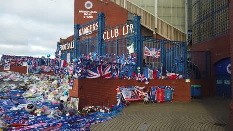 A-side-wide-shot-of-football-fans-tributes-at-the-main-gates-of-Rangers-FC-to-former-manager,-Walter-Smith