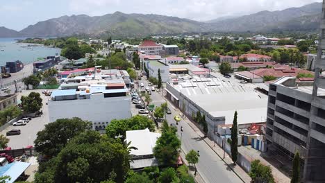 Aerial-drone-rising-over-the-busy-capital-city-with-traffic,-buildings-and-landscape-in-Dili,-Timor-Leste,-Southeast-Asia