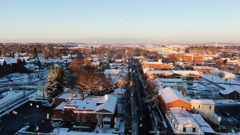 AERIAL-Dolly-Back-Downtown-Lititz-During-Snowfall-At-Sunset