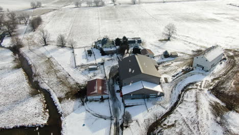 AERIAL-Over-Farmhouse-During-Snow-Storm,-White-Snow-Covered-Fields