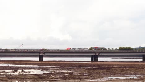 A-shot-of-a-bus-travelling-across-the-Cinta-Costera-bridge,-below-the-sand-and-ground-of-the-Panama-Canal-as-the-ocean-water-has-retracted-during-the-low-tide,-Panama-City