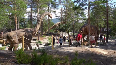 Parque-Temático-Dinosauria-En-Noruega---Día-Soleado-Con-Familias-Disfrutando-De-Vacaciones-Alrededor-De-Modelos-De-Dinosaurios-Reales
