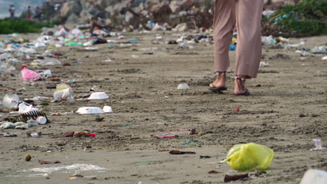 Die-Füße-Einer-Frau-Laufen-Am-Umweltverschmutzten,-Schmutzigen-Strand-Mit-Müll
