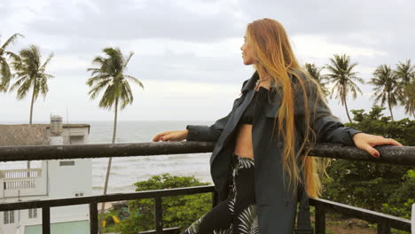 Weibliches-Model-Posiert-Auf-Balkon-Mit-Tropischem-Hintergrund-Aus-Palmen-Und-Dem-Meer