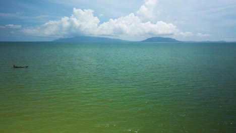 Vista-Del-Océano-Azul-Verde-Esmeralda,-Isla-En-El-Horizonte,-Viajes-En-Bote-Pequeño-En-La-Escena-De-Entrada-Y-Salida-Horizontal-Del-Mar,-Nubes-Esponjosas-En-La-Distancia