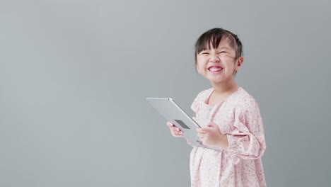 Child-watching-cartoon-with-digital-tablet-in-studio-with-gray-background