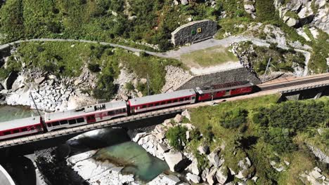 Aerial:-red-train-crossing-a-bridge-and-entering-a-tunnel-close-to-devil's-bridge