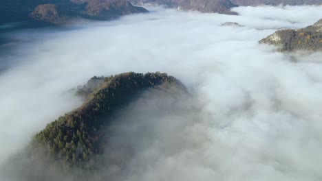 Aerial-view-of-valley-amidst-huge-mountains,-all-covered-with-thick-blanket-of-dense-clouds