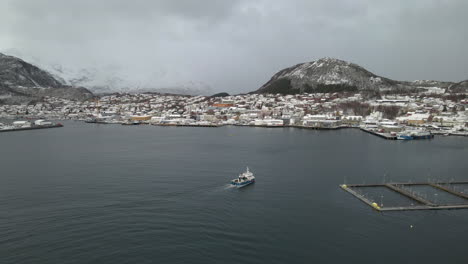 Fishing-boat-cruising-past-salmon-pens-arriving-back-at-Skjervoy-harbor,-Norway