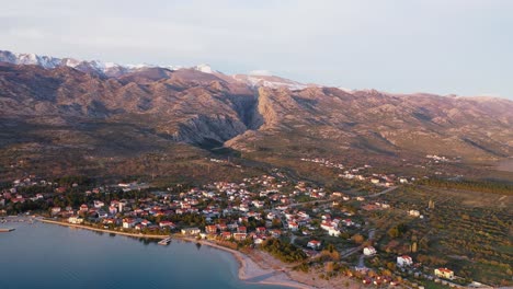 Luftaufnahme-Des-Dorfes-Seline-Mit-Dem-Nationalpark-Nördlicher-Velebit-Im-Hintergrund-In-Kroatien