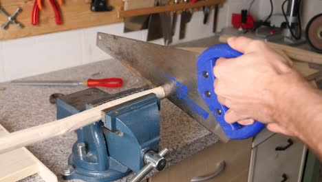 Cutting-wood-rods-with-hand-saw-at-workshop-wrench