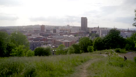 Stabilised-gimbal-shot-of-man-with-backpack-with-camera-taking-photos-of-Sheffield-city-skyline-from-Sheaf-Valley-Park