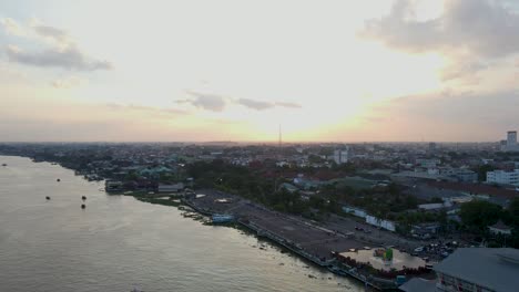 Majestic-sunset-over-Palembang-city-with-vast-Musi-river,-aerial-fly-back-view