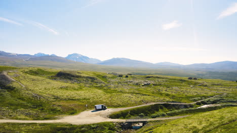 Vehículo-En-La-Carretera-En-Medio-De-La-Pradera-Verde-Y-La-Cordillera-En-El-Parque-Nacional-De-Rondane-En-Noruega