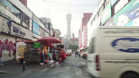 A-typical-street-in-Centro-Histórico,-Mexico-City-with-street-food-sellers,-retail-stores,-historic-church-and-a-satellite-tower-in-background