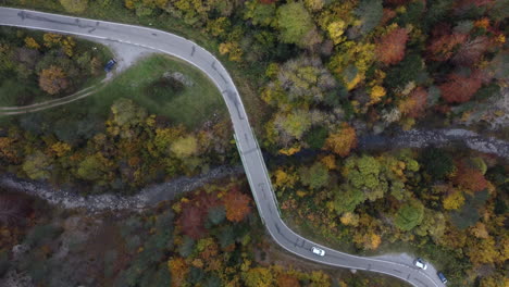Luftaufnahmen-Eines-Weißen-Autos,-Das-Im-Herbst-In-Nordspanien-Bei-Wunderschönem-Sonnenuntergang-Eine-Brücke-über-Den-Fluss-Im-Bergwald-Der-Pyrenäen-überquert