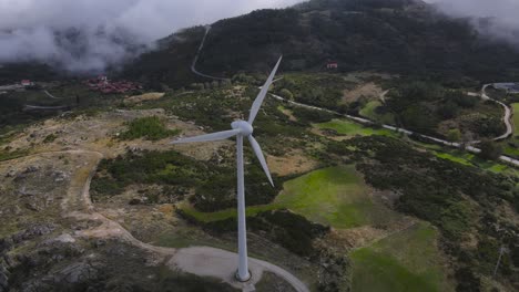 Aerial-circling-around-wind-turbines-with-blades-spinning,-Caramulo