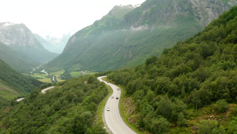 Driving-Cars-On-Curved-Road-On-Mountain-Surrounded-With-Lush-Green-Forest-In-Stryn,-Norway