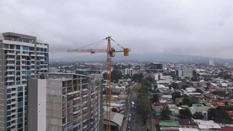 Drone-shot-of-a-crane-constructing-a-skyscraper-in-San-Jose-city,-Costa-Rica