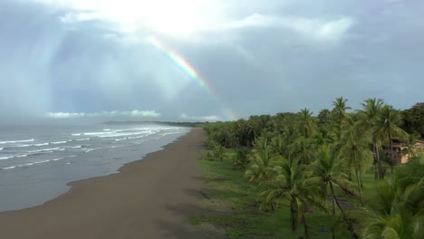 Beautiful-drone-shot-of-a-rainbow-over-a-beach-on-a-tropical-paradise-island
