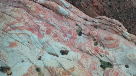 View-from-a-drone-of-a-massive-rock-formation-with-a-red-orange-marble-texture-in-the-mountains-during-the-day