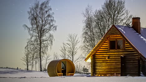 night-timelapse-over-a-tub-sauna-and-wood-chalet-covered-in-snow,-in-wild-winter-field