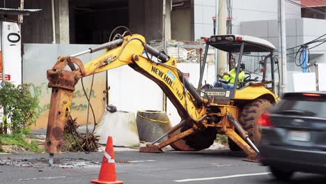 Hydraulic-breaker-bulldozer-breaks-asphalt-in-Panama-City,-Panama,-wide-shot,-Road-digging-to-repair-or-replace-water-pipes