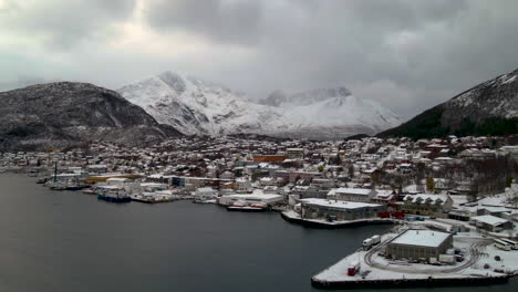 Calm-Fjord-And-Fishing-Village-In-Skjervoy-Island-In-Northern-Troms,-Norway-With-Snowy-Alpine-Mountains-In-Background-On-A-Dramatic-Winter-Day