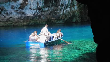 Melissani-Lake---Boatman-Rowing-Boat-With-Tourists-On-Clear-Waters-Of-Lake-In-Melissani-Cave-In-Greece
