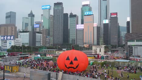 Eine-Riesige,-10-Meter-Hohe-Aufblasbare-Halloween-Kürbisinstallation-Wird-Von-Der-Öffentlichkeit-Während-Der-Halloween-Feierlichkeiten-Genossen,-Während-Im-Hintergrund-In-Hongkong-Eine-Skyline-Aus-Wolkenkratzern-Zu-Sehen-Ist